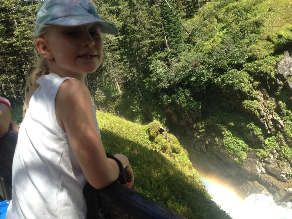 Mein Sohn am Geländer des Panoramawegs, mit Regenbogen in der Gischt der Krimmler Wasserfälle