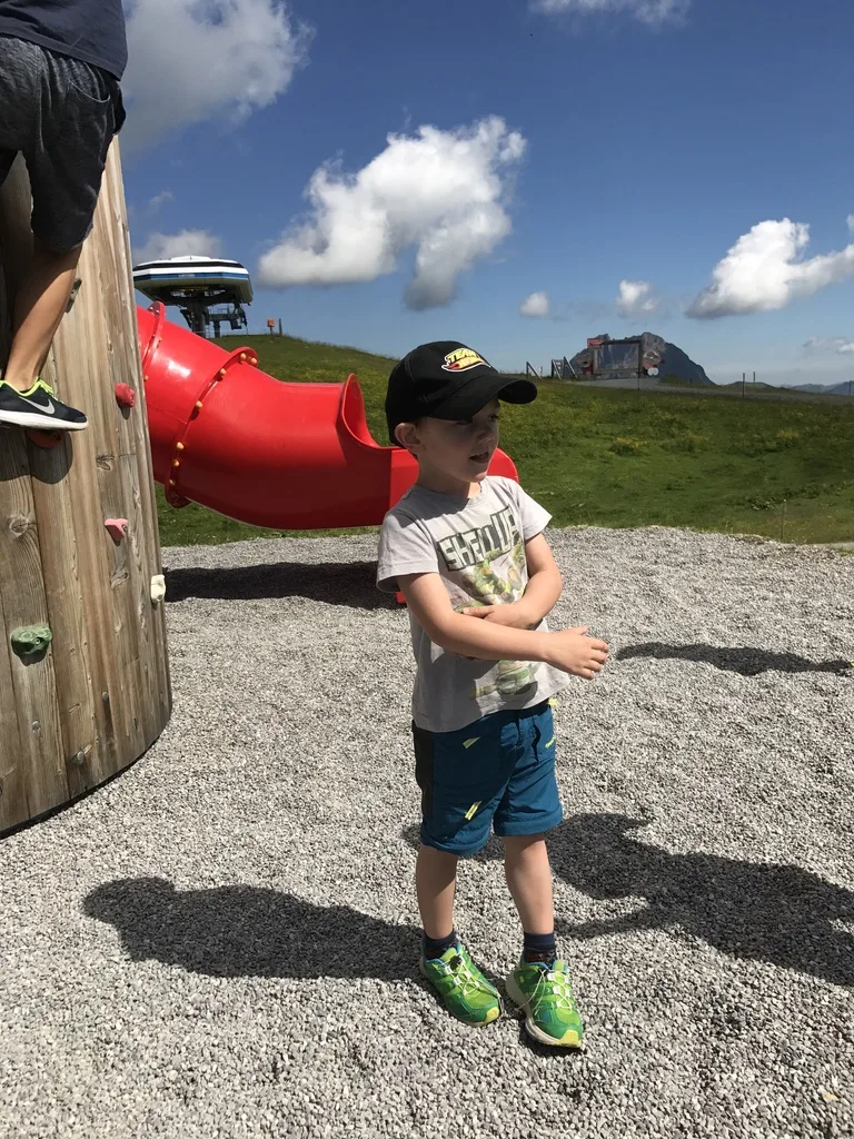 Bub am Spielplatz an der Wildkogel-Bergstation mit Tunnelrutsche und Bergpanorama